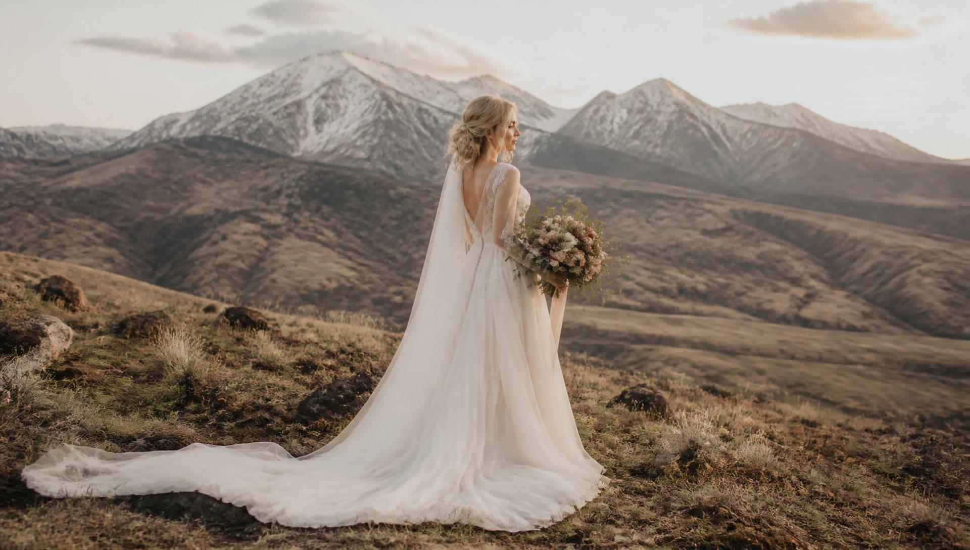 Bride framed by dusty-rose silk draping over a weathered stone arch